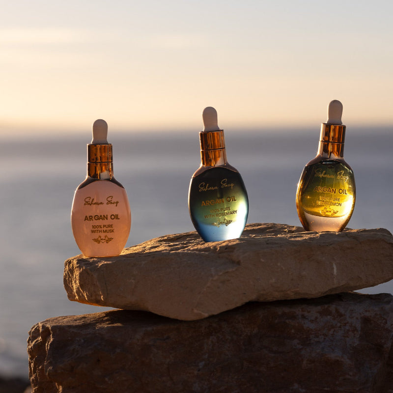 Three dropper bottles bottles luxury style golden lid op top of rock in front of the sea